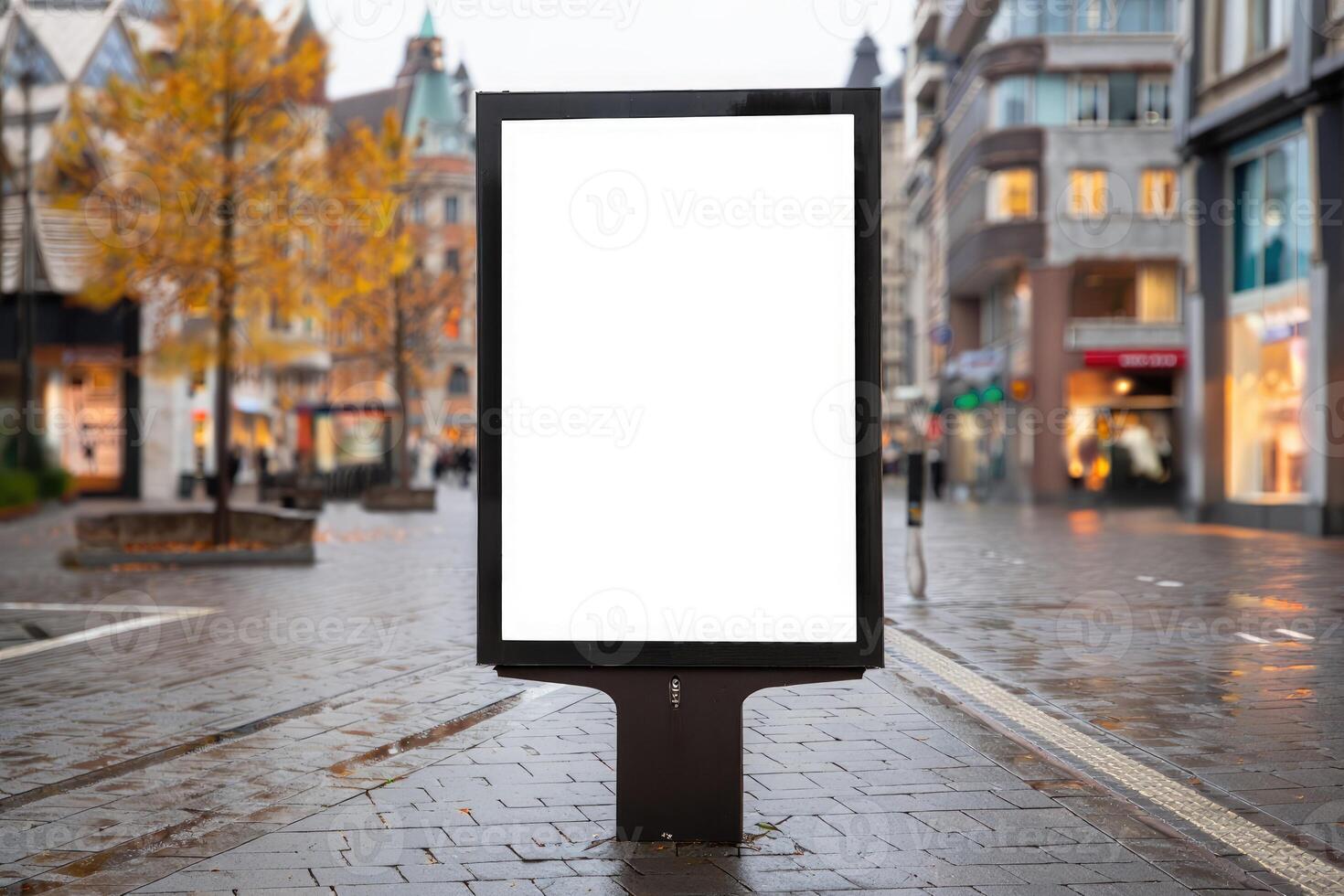 Blank advertising billboard located on a busy urban street during a rainy afternoon photo
