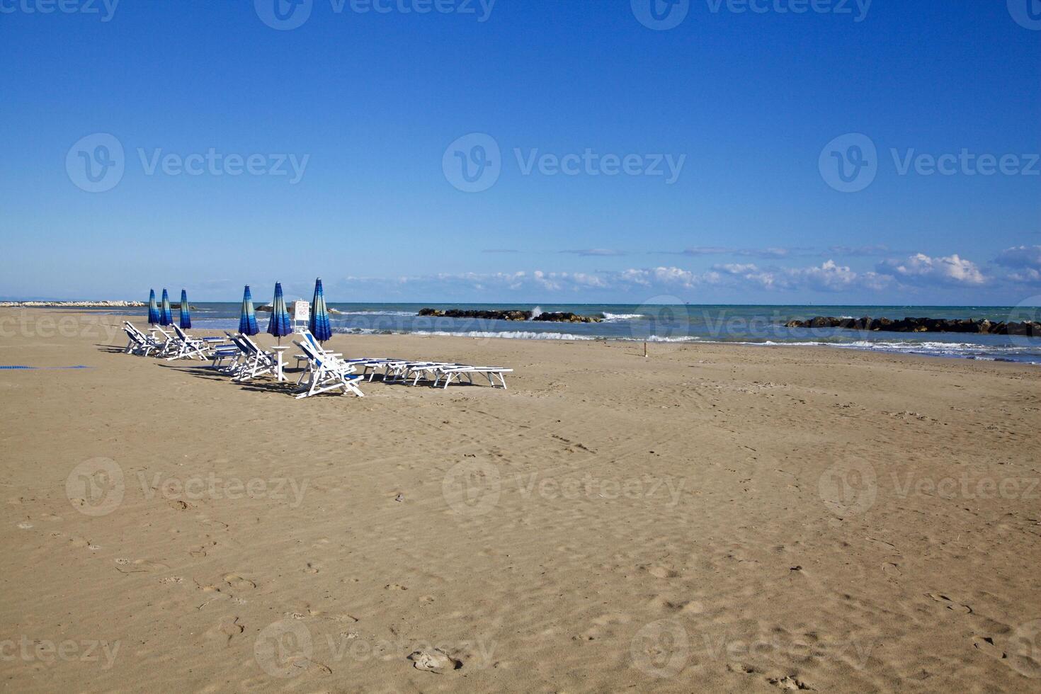 Deck chairs and parasols on an empty beach in winter on a sunny day photo