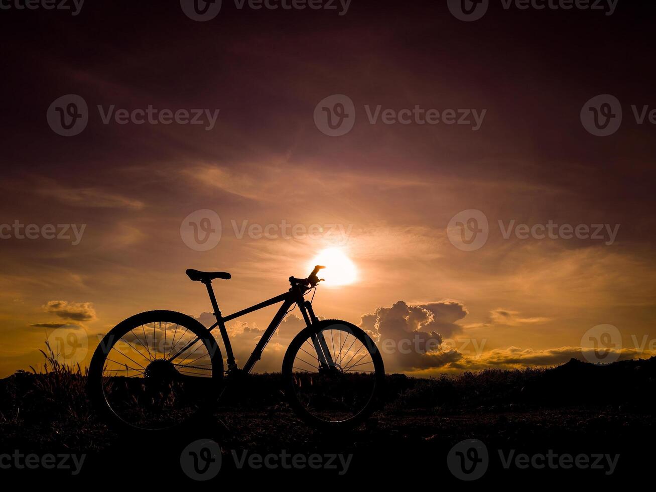 Silhouette of Mountain Bike Against Dramatic Sunset Sky with Clouds in the Background photo