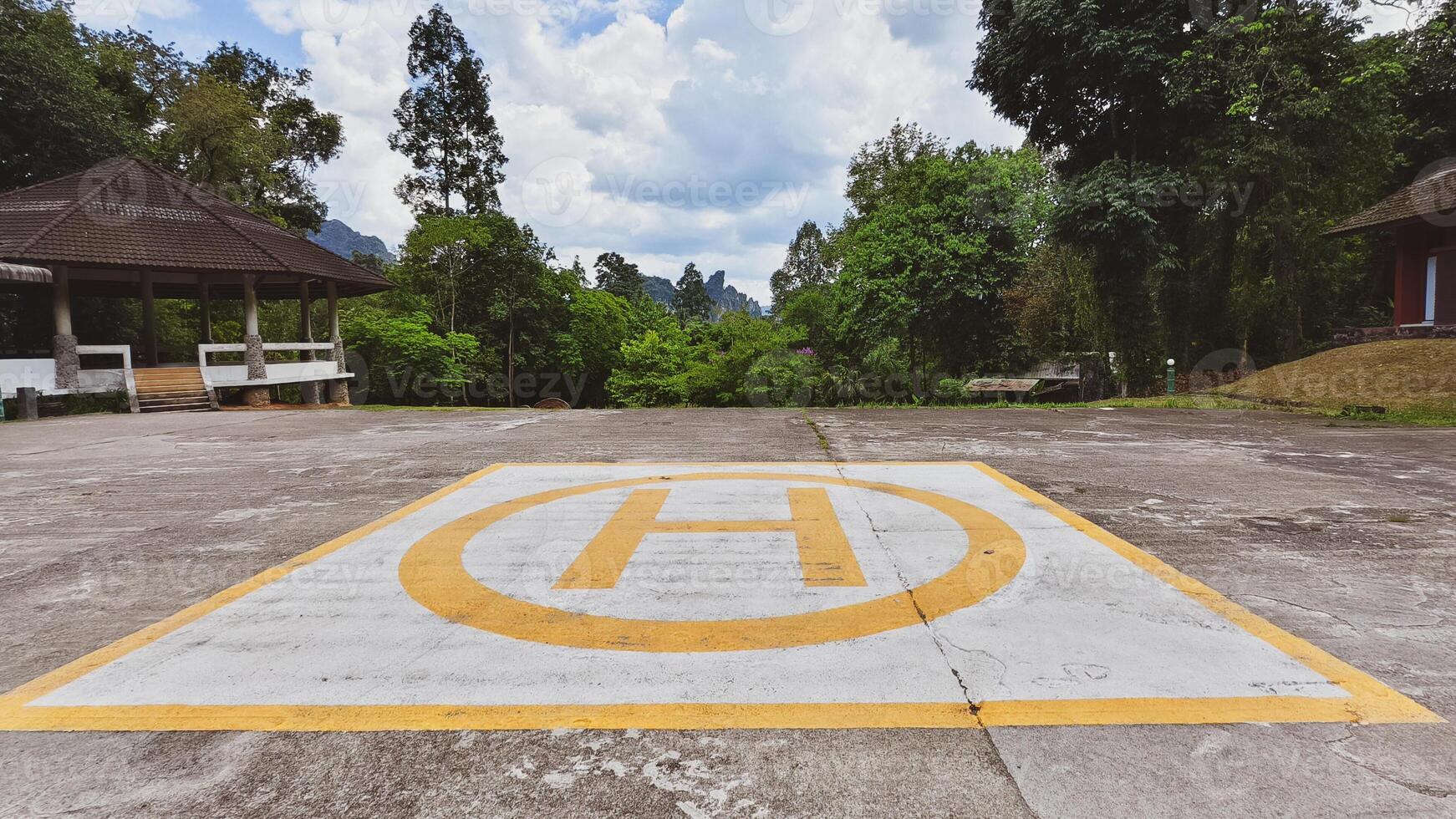 Helipad in Scenic Forest Setting with Lush Greenery and Cloudy Sky in the Background photo