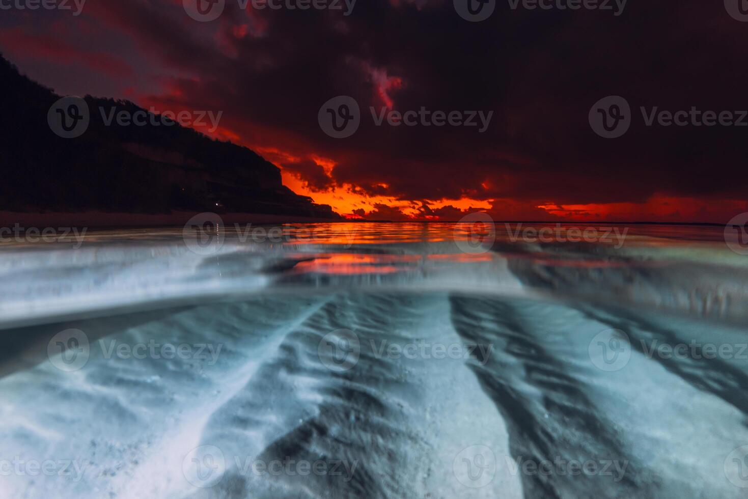 Sunset over calm sea with underwater sand patterns, captured in a split-view seascape photo