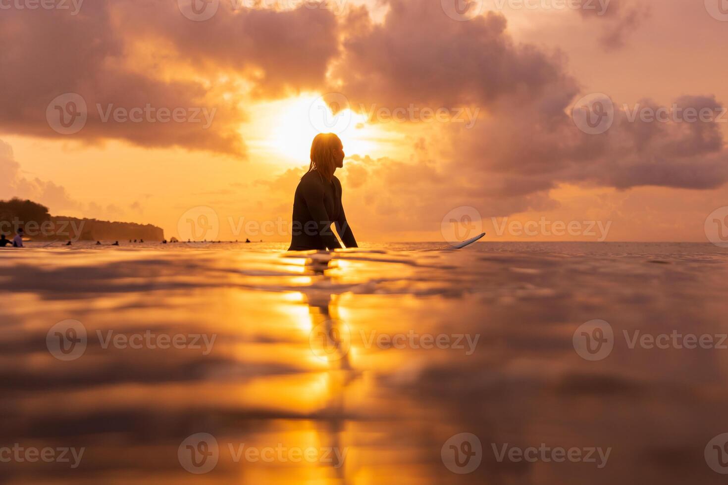 Surfer waiting for a wave at golden sunset, reflecting peaceful vibes and ocean adventure moments photo