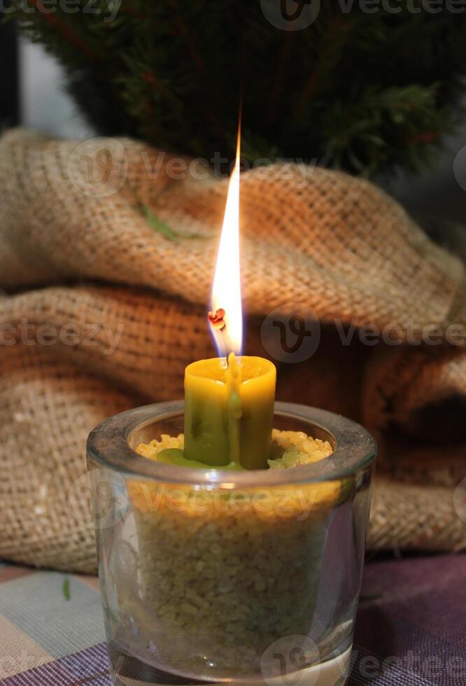 Traditional Candle Injected In Wheat Corns Inside Glass Burning In Front Of Spruce In Craft Folded Fabric photo