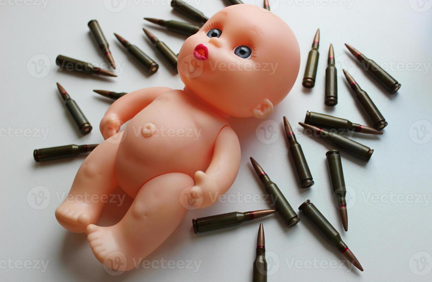 Baby Doll With Sad Eyes On Scattered Bullets On Clean White Surface Stock Photo