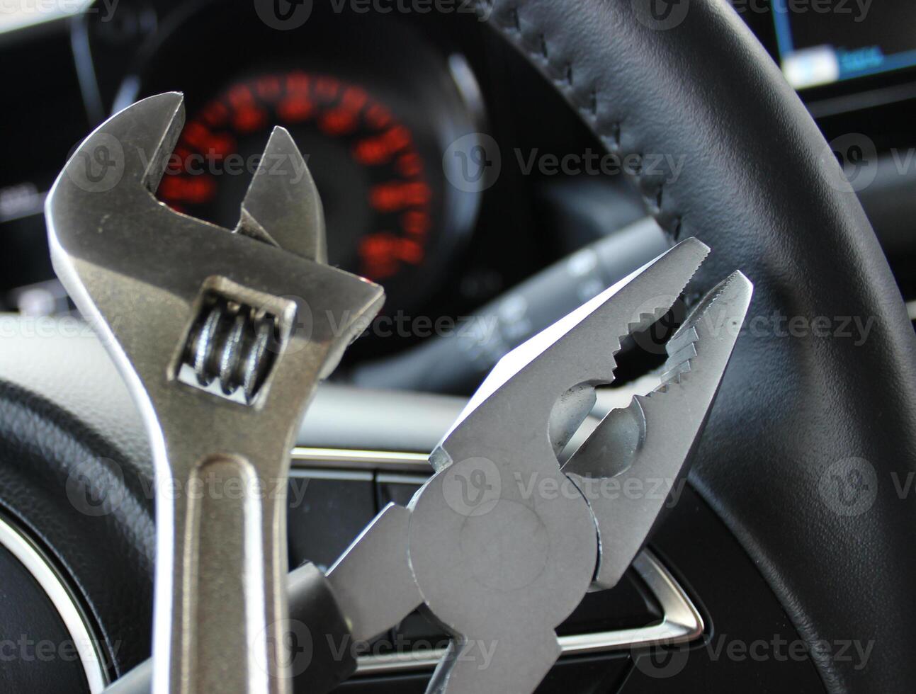 Car Inspection Image. Crossed pliers and adjustable wrench over defocused steering wheel in a car photo