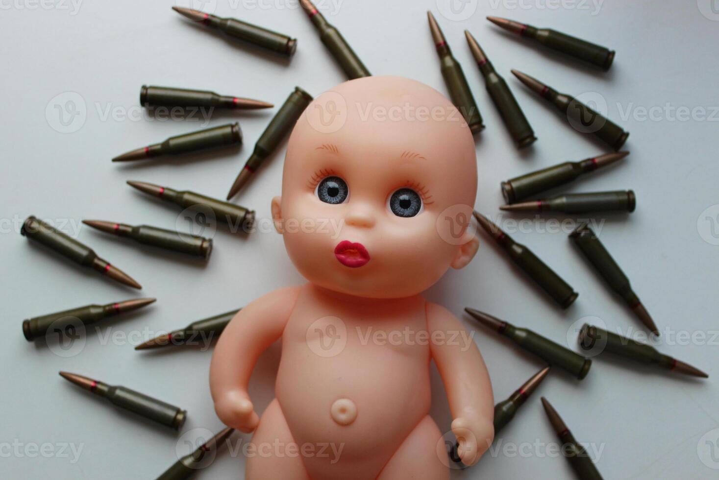 Lost Childhood Concept Photo. Naive face of a child's doll lying on a bullets top view photo