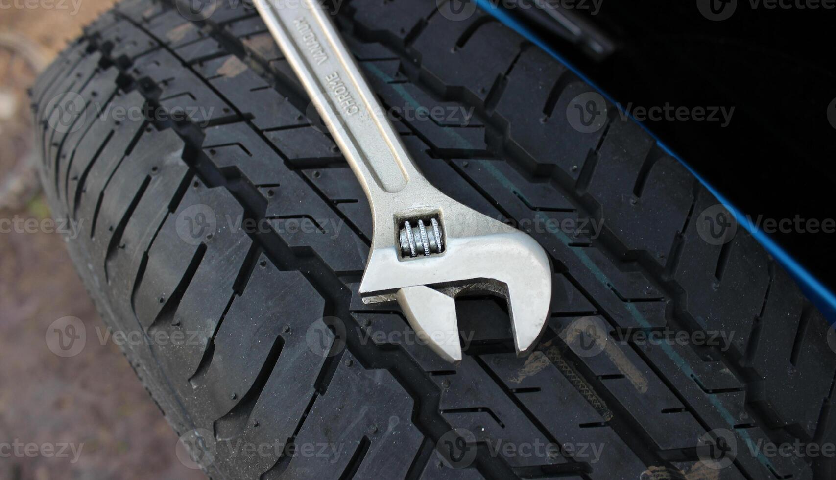Chrome adjusting wrench lie on the spare wheel attached to the trunk door of the SUV car photo
