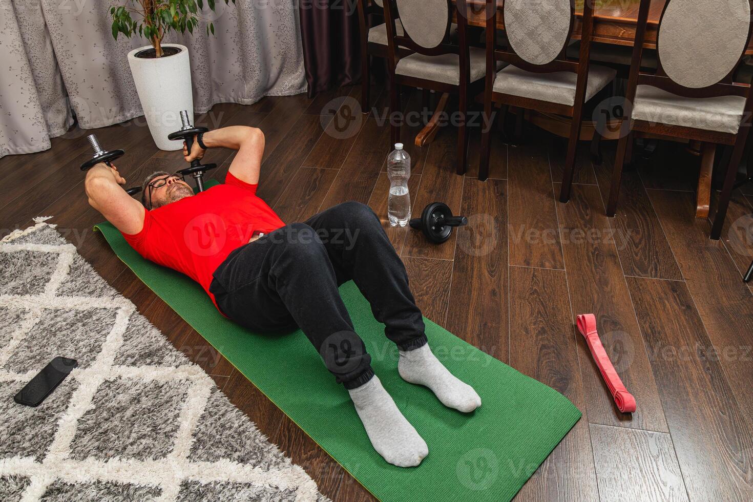 Man exercising with dumbbells at home in living room photo