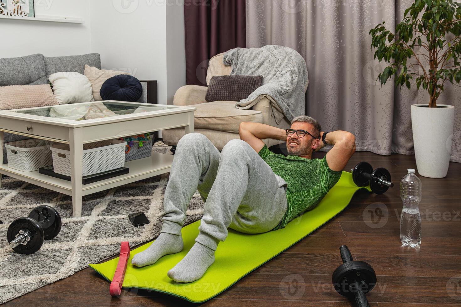 Man exercises at home using a yoga mat and weights photo