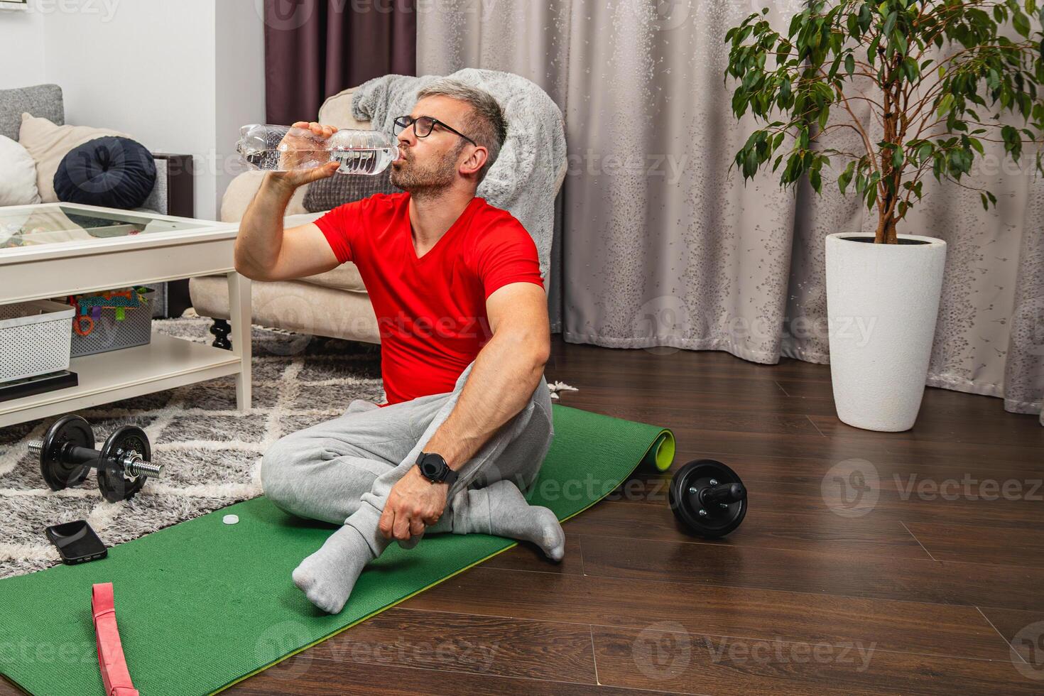 Man exercising at home while taking a water break photo