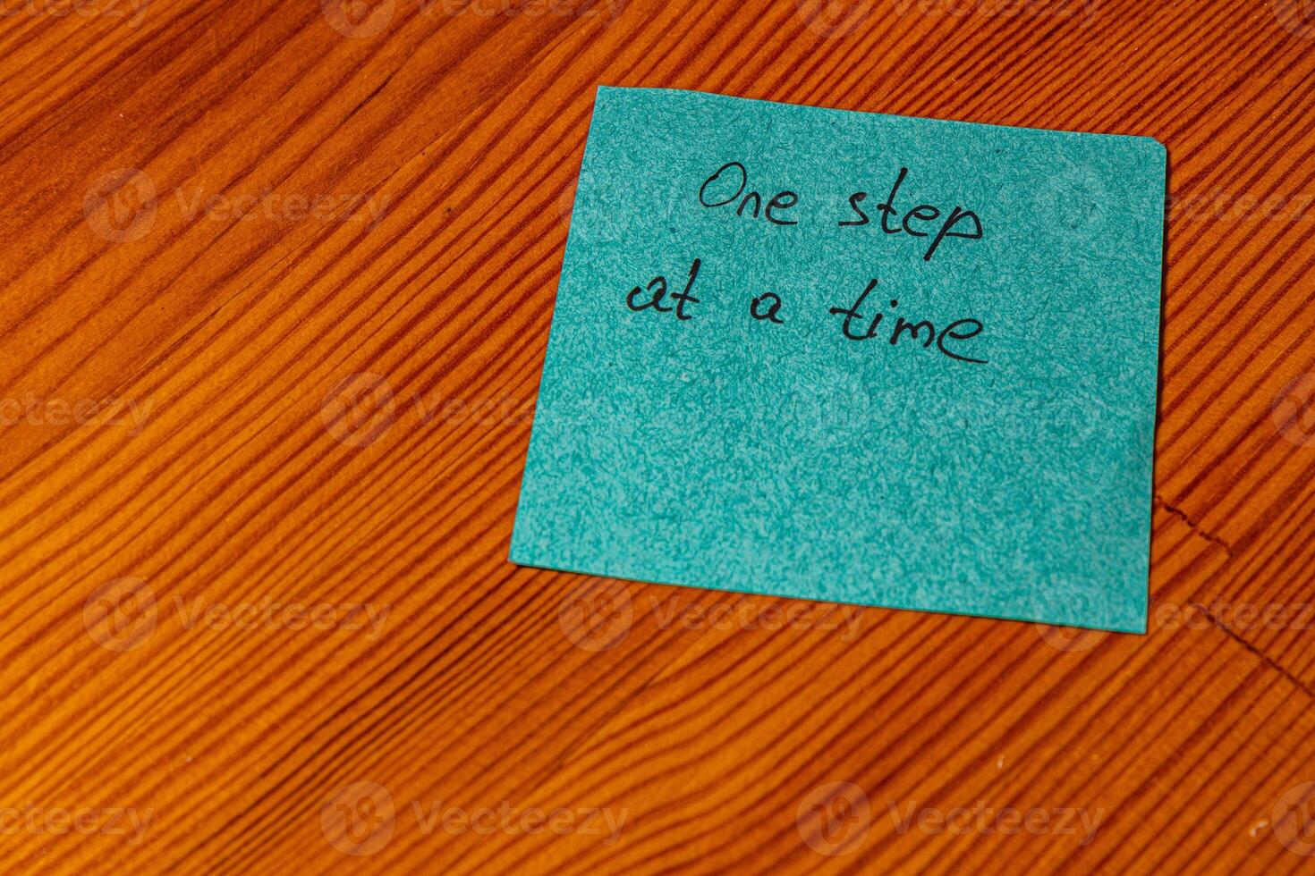 Motivational note on a wooden surface encouraging a steady approach to tasks photo