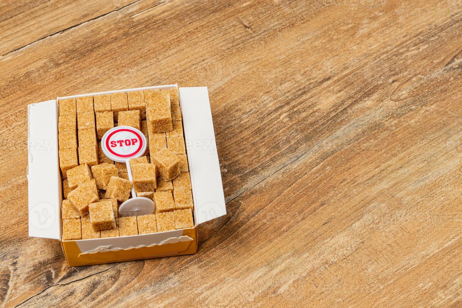 Brown sugar cubes in a box with a stop sign on a wooden surface photo