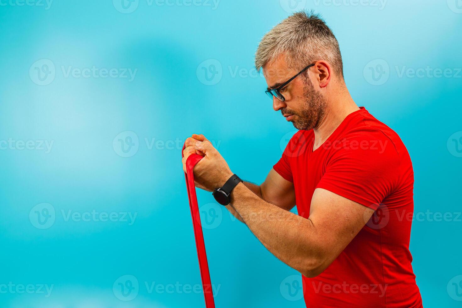 Man exercises with resistance. band against blue backdrop photo