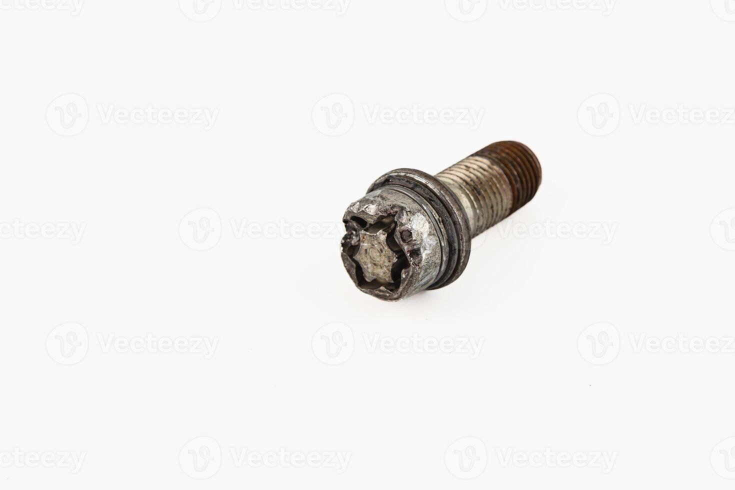Broken bolt lying on a surface with a damaged wheel nearby photo