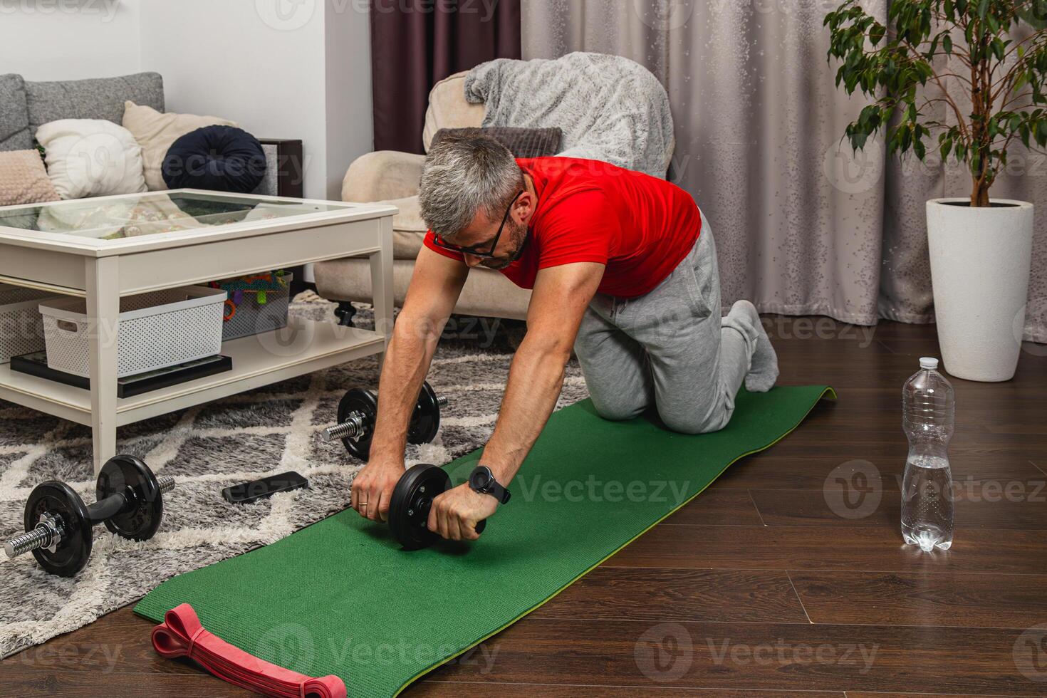 Man exercising at home using an ab roller on a mat photo