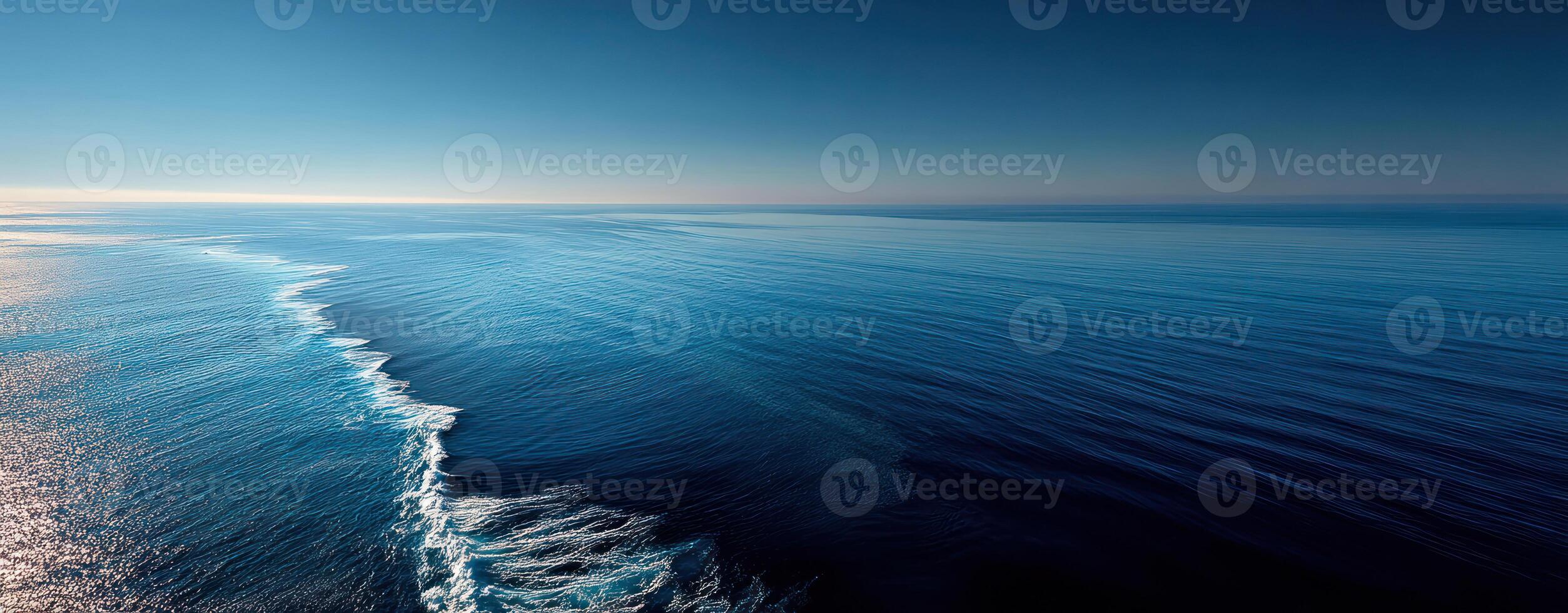Calm blue sea below viewed from plane circling before landing with peaceful horizon and gentle waves under clear sky photo