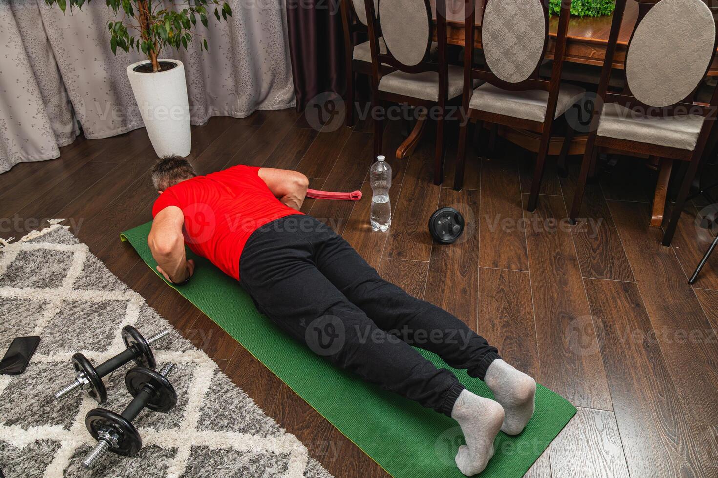 Man exercising indoors on fitness mat with dumbbells photo