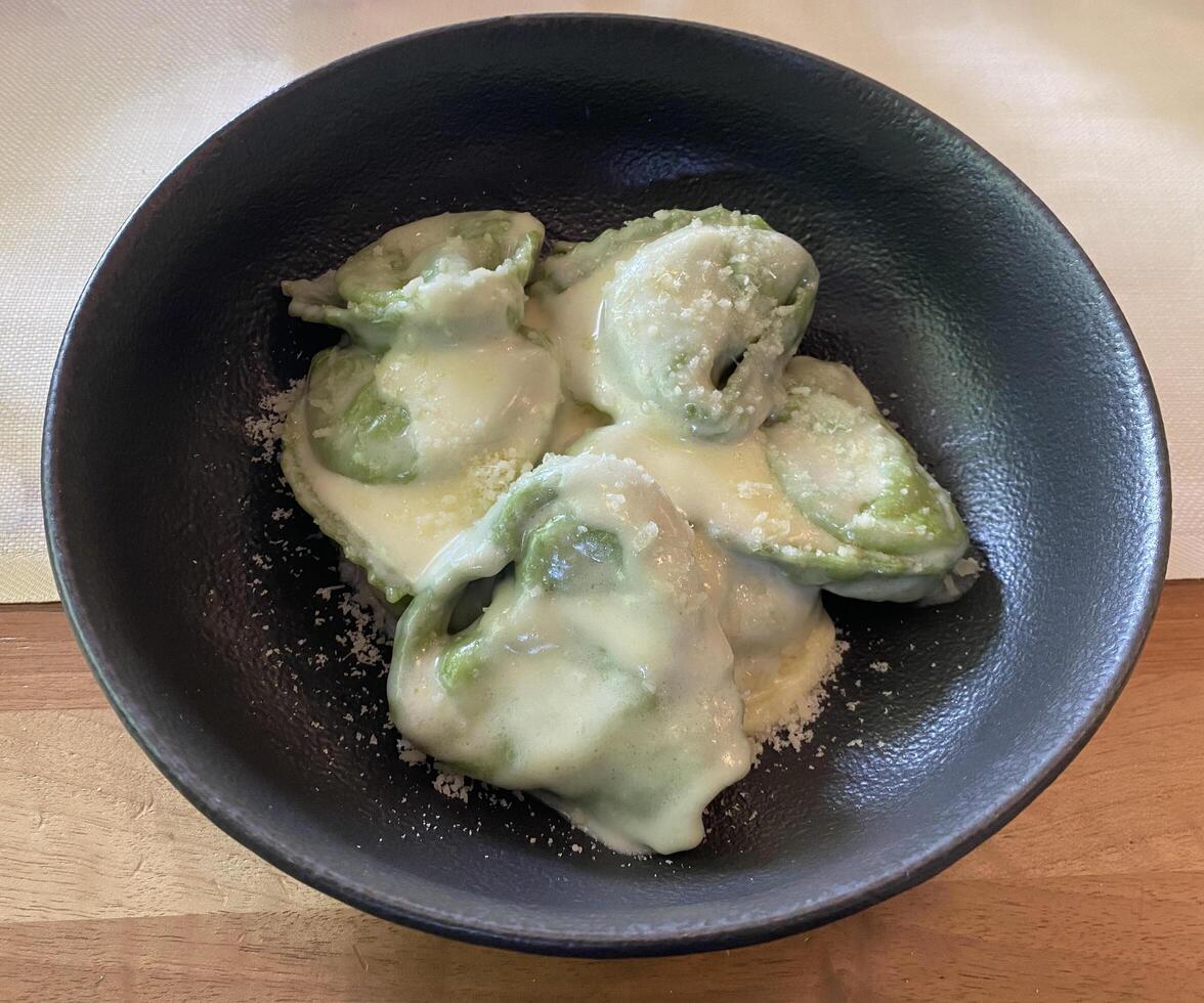 Italian Balanzoni in Parmigiano Reggiano Cream. A classic Bolognese stuffed pasta, crafted from the tradition of reusing leftover tortellini and enriched with ricotta and spinach. photo