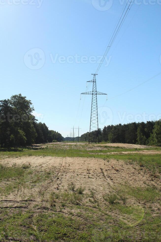 a tower for wires. A line of high-voltage wires under voltage runs through the entire forest. photo