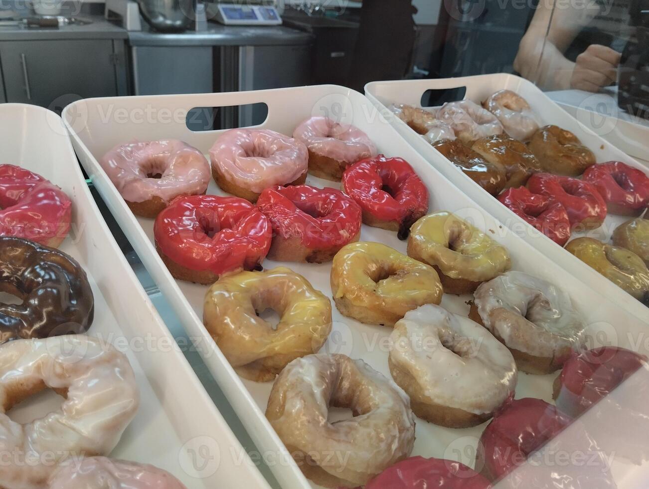 Donuts in a tray with colored glaze and sprinkled with chocolate nuts. National Sweetness photo
