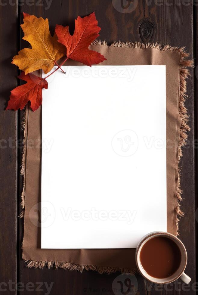 Autumn leaves and blank paper with coffee on rustic wooden table background. Space for text photo