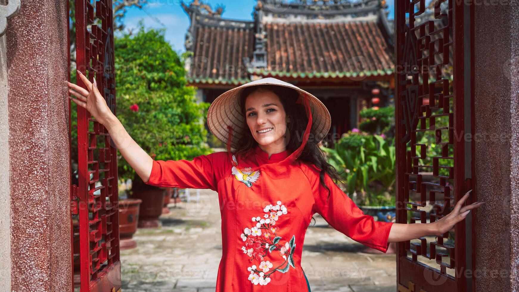 a female tourist in a hat and a traditional Vietnamese dress on the background of a Buddhist temple in Vietnam photo
