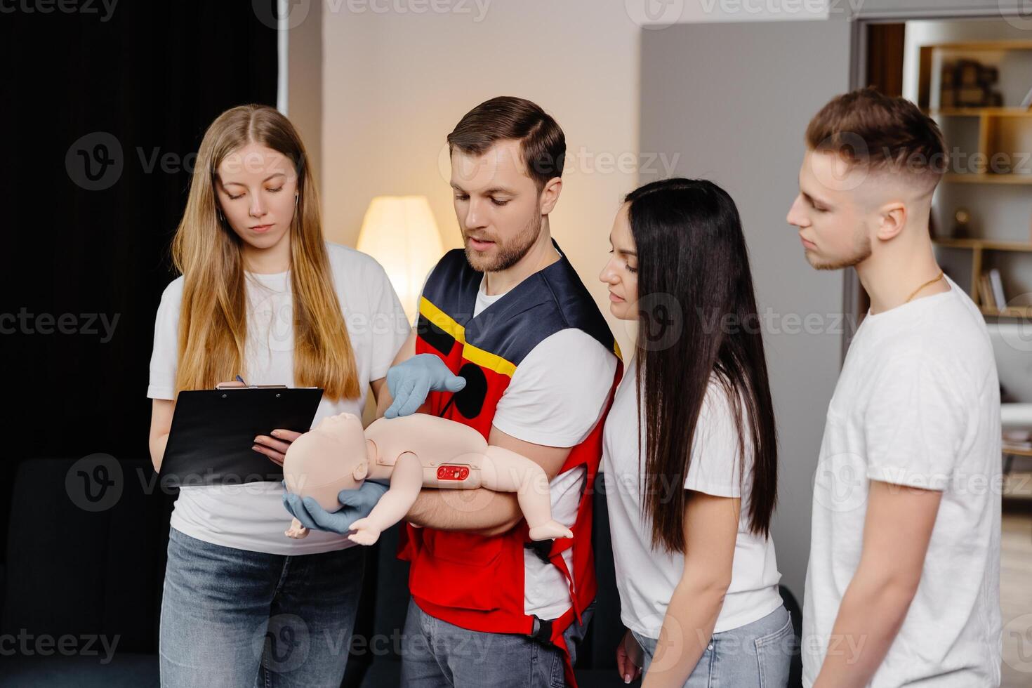 Group of people learning how to make first aid with dummy child during the training indoors. photo