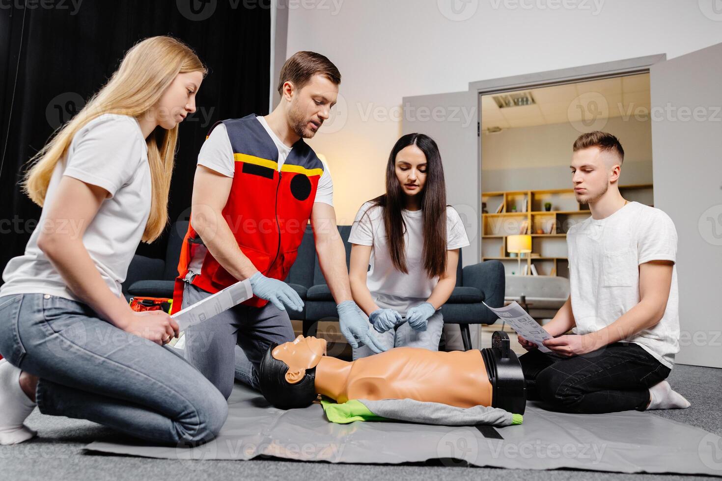 Group of people learning how to make first aid heart compressions with dummies during the training indoors. photo
