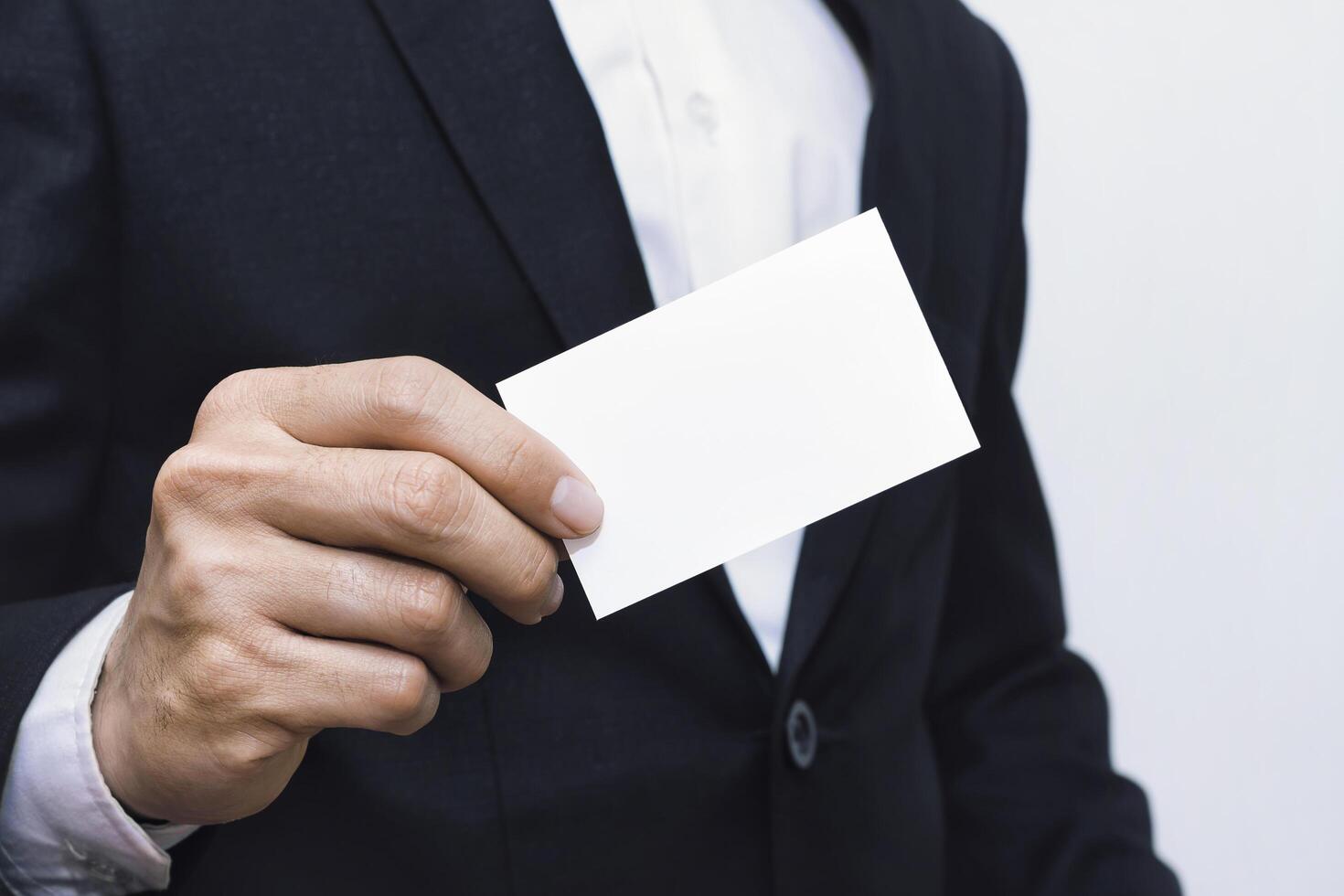Businessmen holding white mockup business card on concrete wall background photo