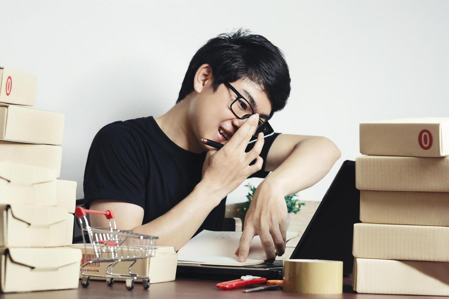 Asian man small business owner, working at home office answer the phone happy after new order from customer, Online marketing packaging, delivery startup SME, entrepreneur or freelance man concept photo