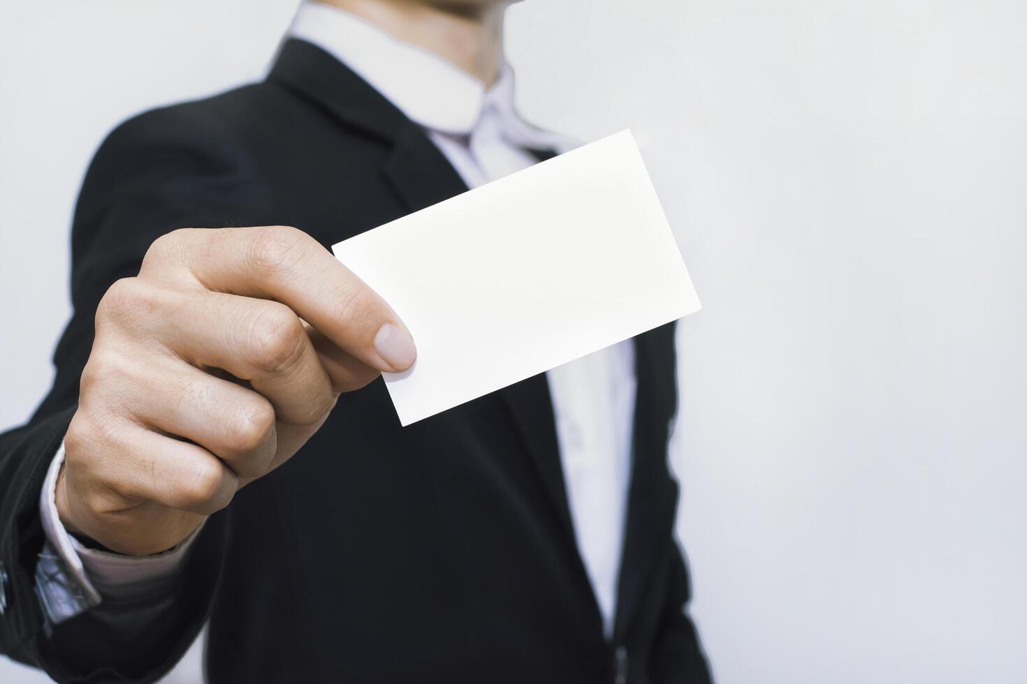 Businessmen holding white mockup business card on concrete wall background. photo