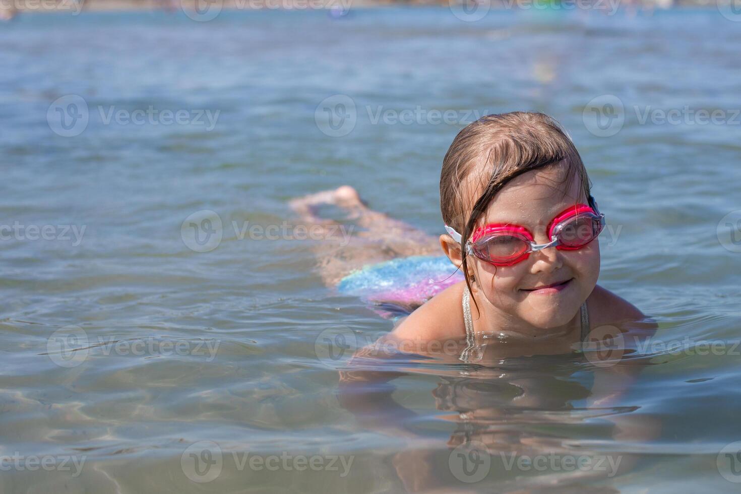 Young girl swimming in clear blue natural waters with goggles. photo