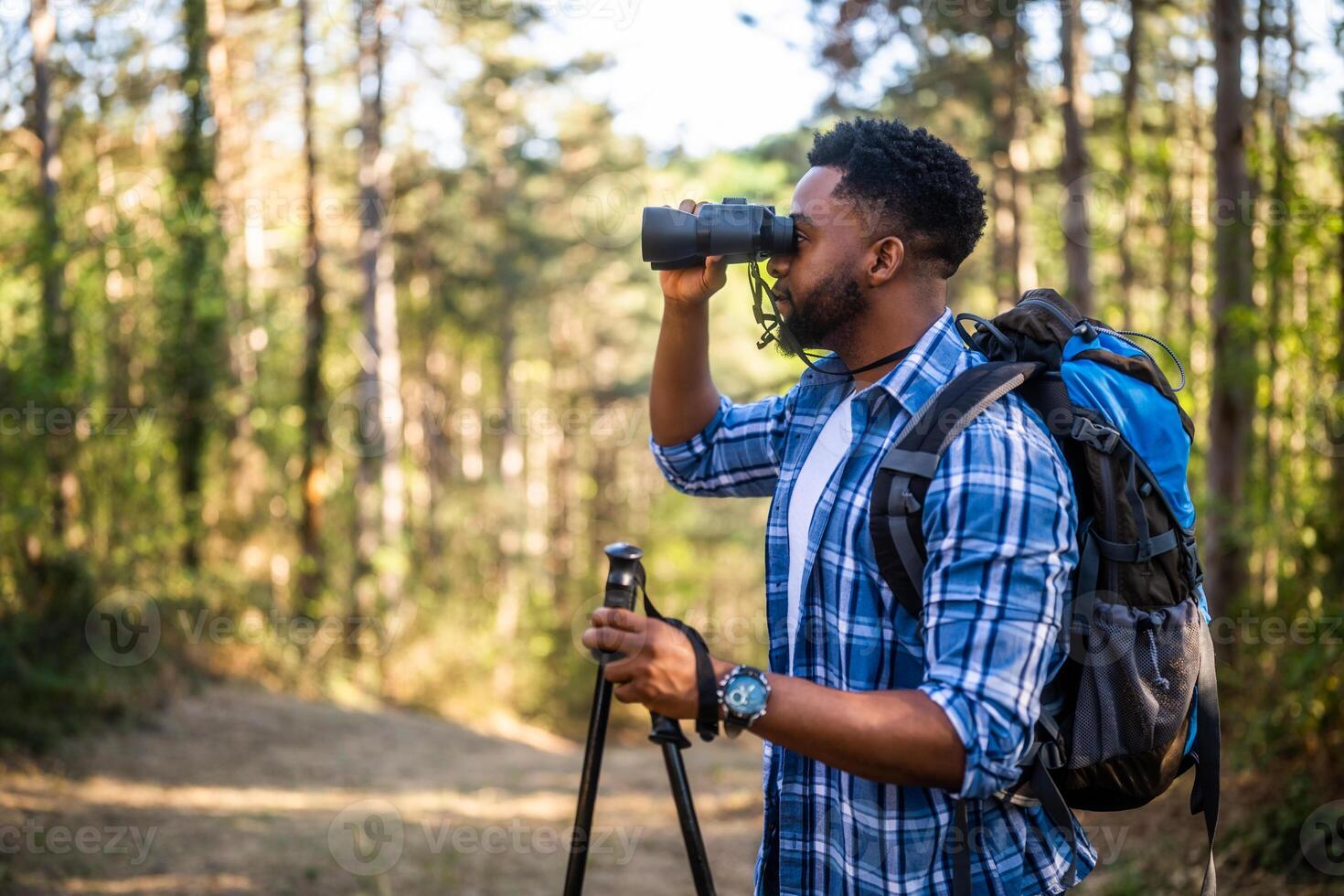 African American man using binoculars to explore the wilderness on a hiking adventure. photo