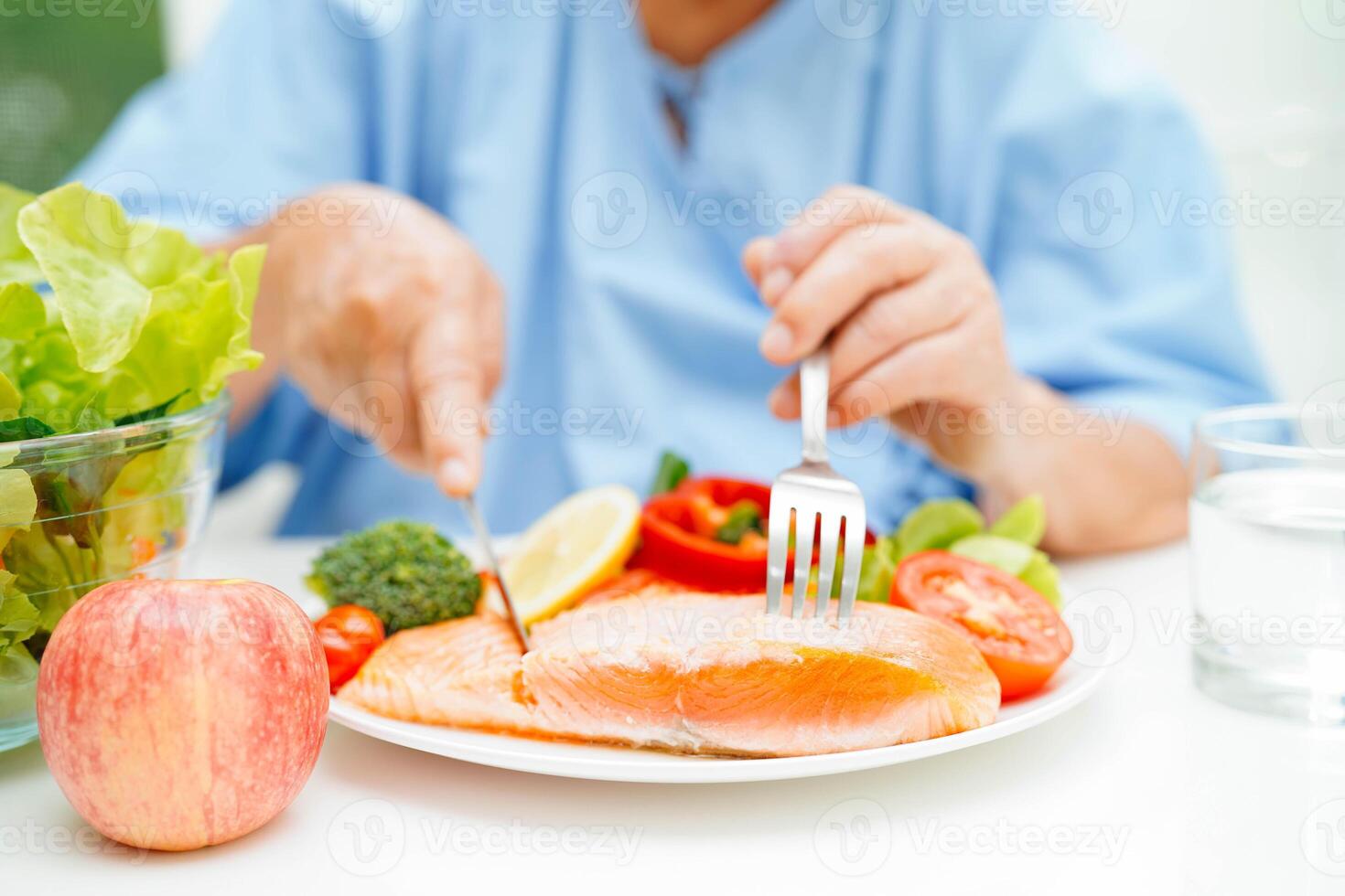 Asian elderly woman patient eating salmon stake and vegetable salad for healthy food in hospi photo