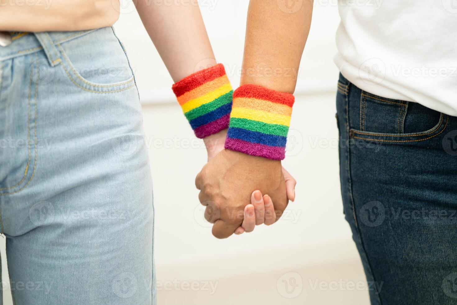 Asian LGBT couple woman holding hand wearing rainbow wristb photo