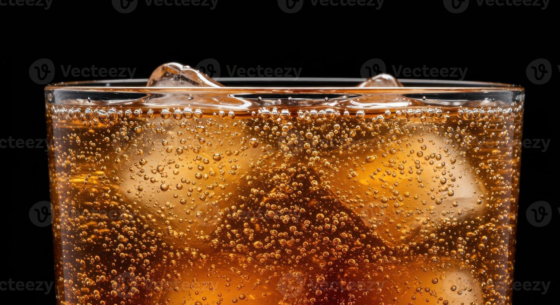Refreshing caramel colored carbonated drink with ice cubes in a glass, showcasing effervescence and condensation on a black background. photo