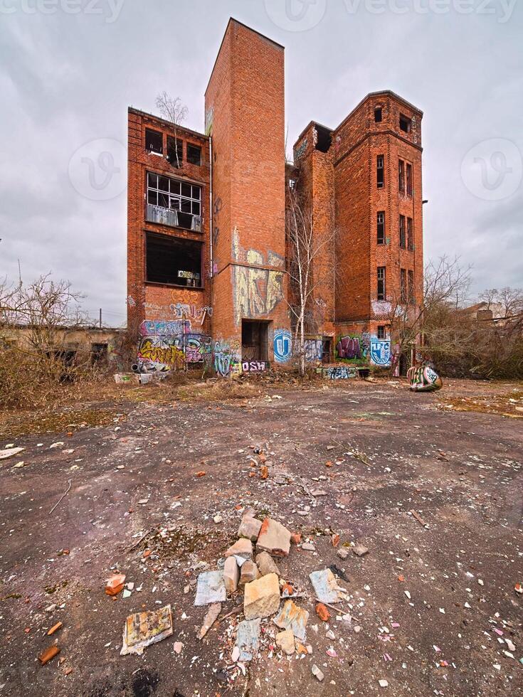 Abandoned brick factory in Germany with graffiti-covered walls, broken windows, and overgrown surroundings photo