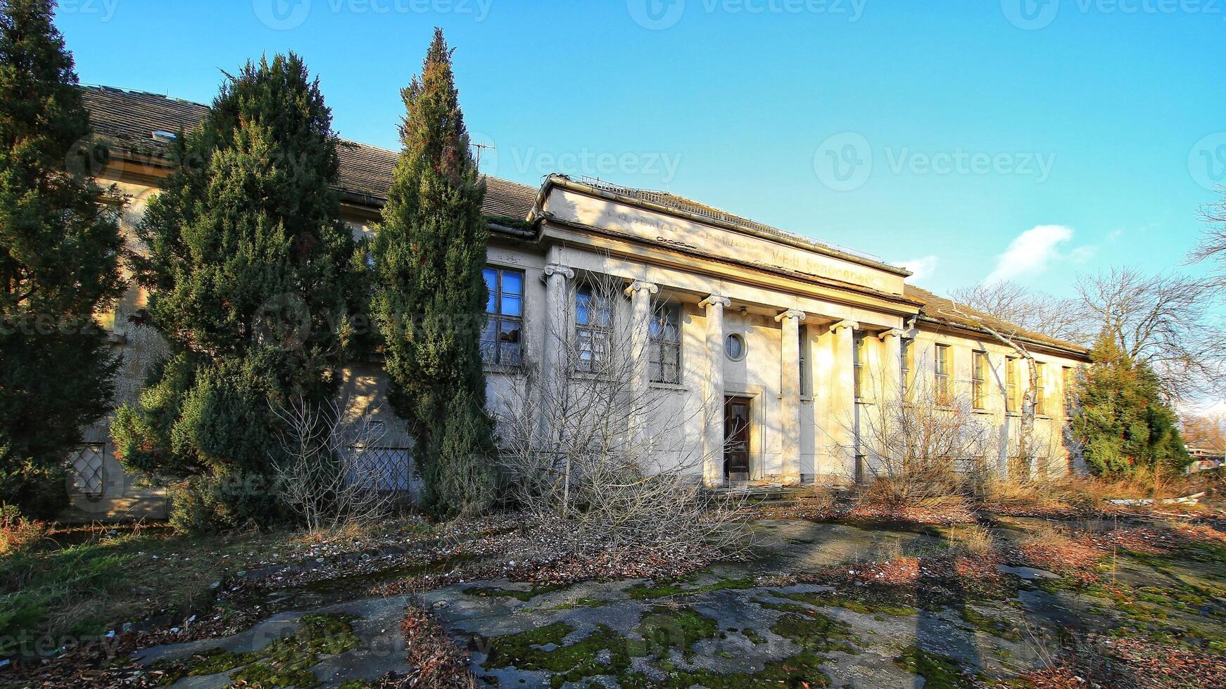 Abandoned neoclassical building in Schonebeck, Germany, with tall columns, broken windows, and overgrown vegetation photo
