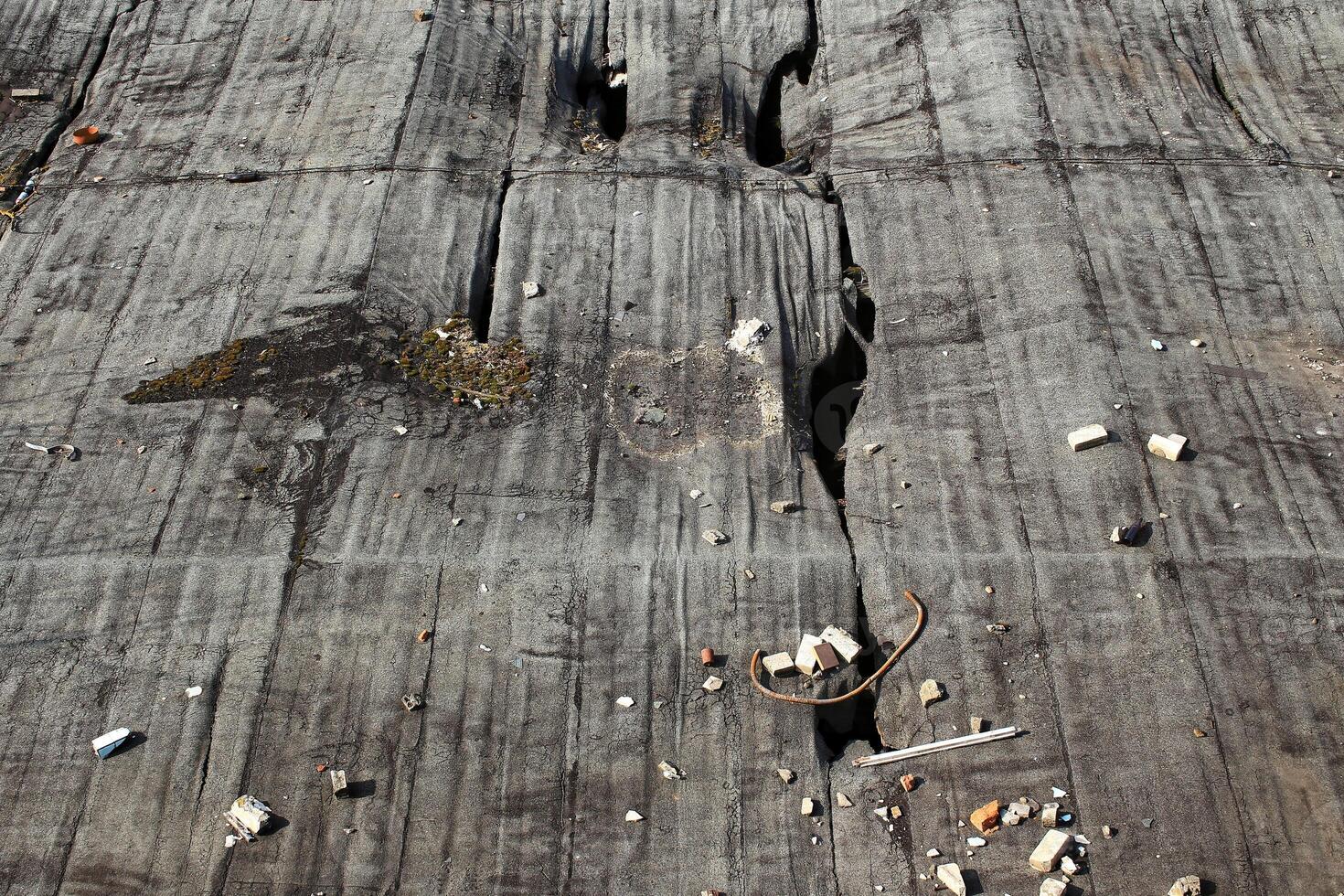 Cracked rooftop surface with scattered debris and visible damage from wear and exposure photo