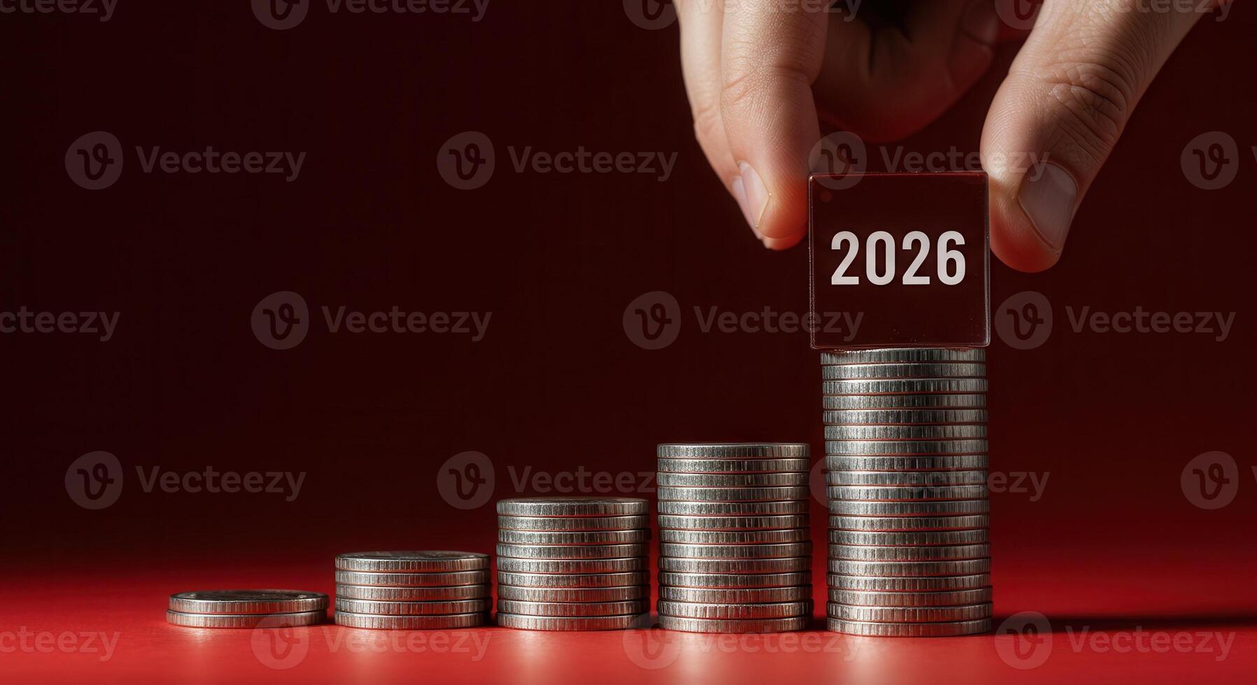 Hand places a cube with 2026 on top of a stack of coins, showing financial growth and future planning for the year 2026. photo