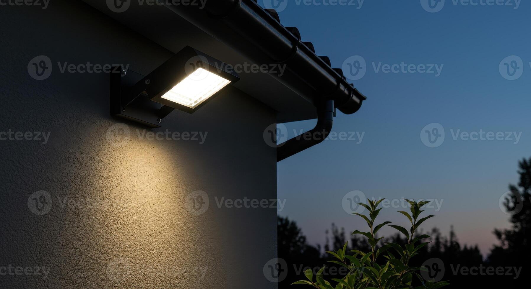 Illuminated outdoor LED light on a house wall at dusk, providing security and enhancing the exterior with energy efficient lighting technology. photo