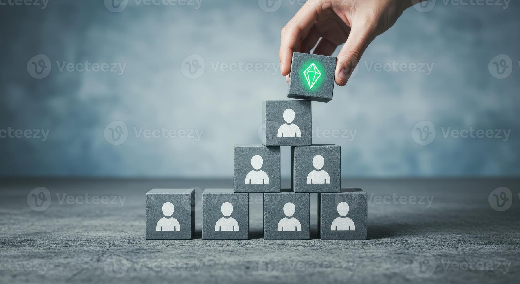Hand placing a block with a diamond icon atop a pyramid of blocks with businessman icons, representing talent, leadership, and hierarchy. photo