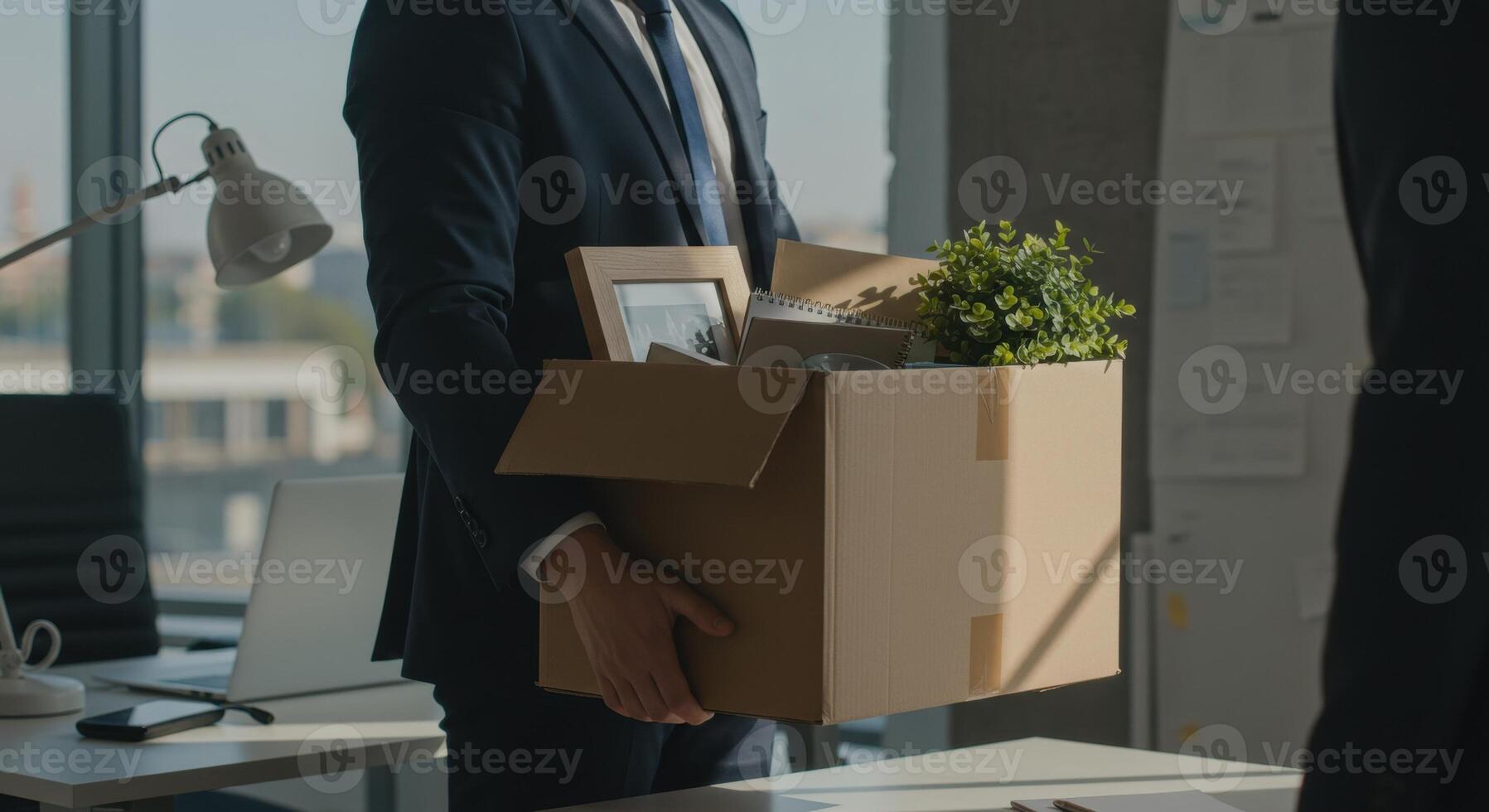 Businessman in suit carries box with personal items after leaving job. Resignation, layoff, career change and unemployment concept. photo