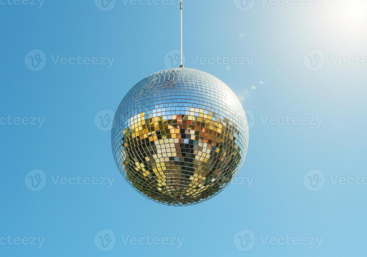 Disco ball hanging against a clear blue sky, reflecting sunlight. Mirror ball, party, celebration, entertainment and festive mood concept with copy space. photo