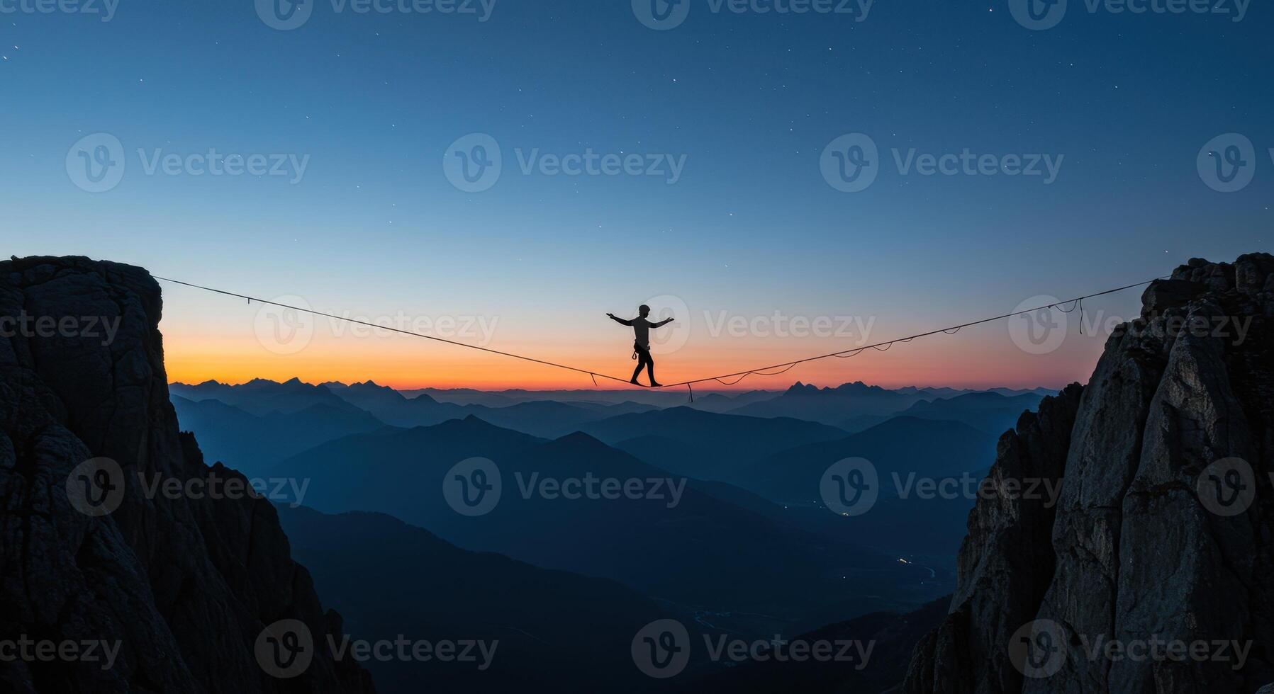 Silhouette of a man balancing on a highline between two mountain peaks at dusk, with a colorful sky and mountain range in the distance. photo