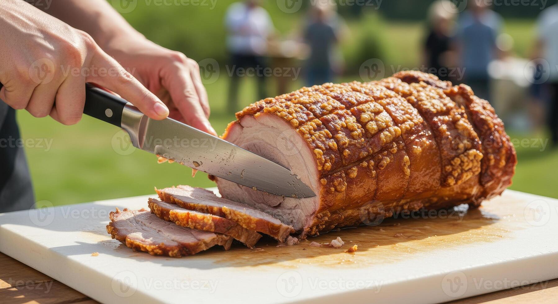 Chef slices crispy pork roast on a cutting board outdoors. Delicious roasted meat with crackling skin, prepared for a summer barbecue party. photo