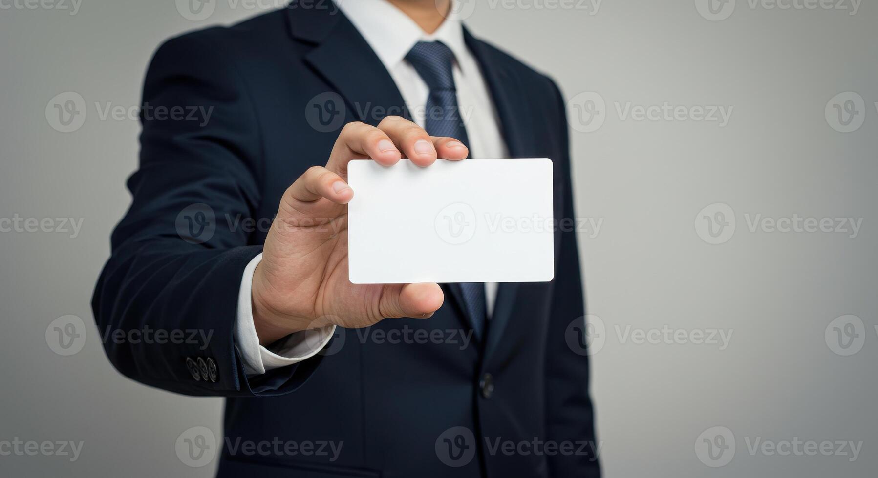 Businessman in suit holds blank white card. Professional presents empty business card for message, contact information, or marketing. Mockup template for design. photo