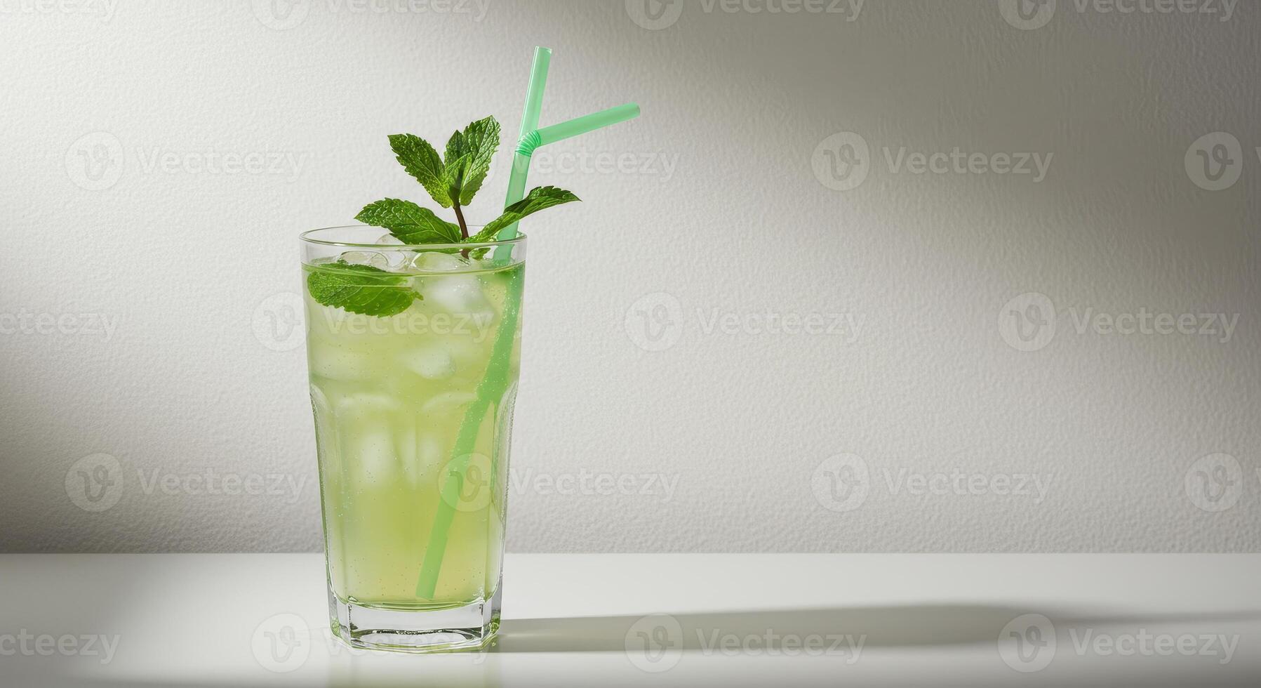 Refreshing mojito cocktail with mint leaves and ice cubes in glass with straw on white surface. Summer drink concept, studio shot, copy space. photo
