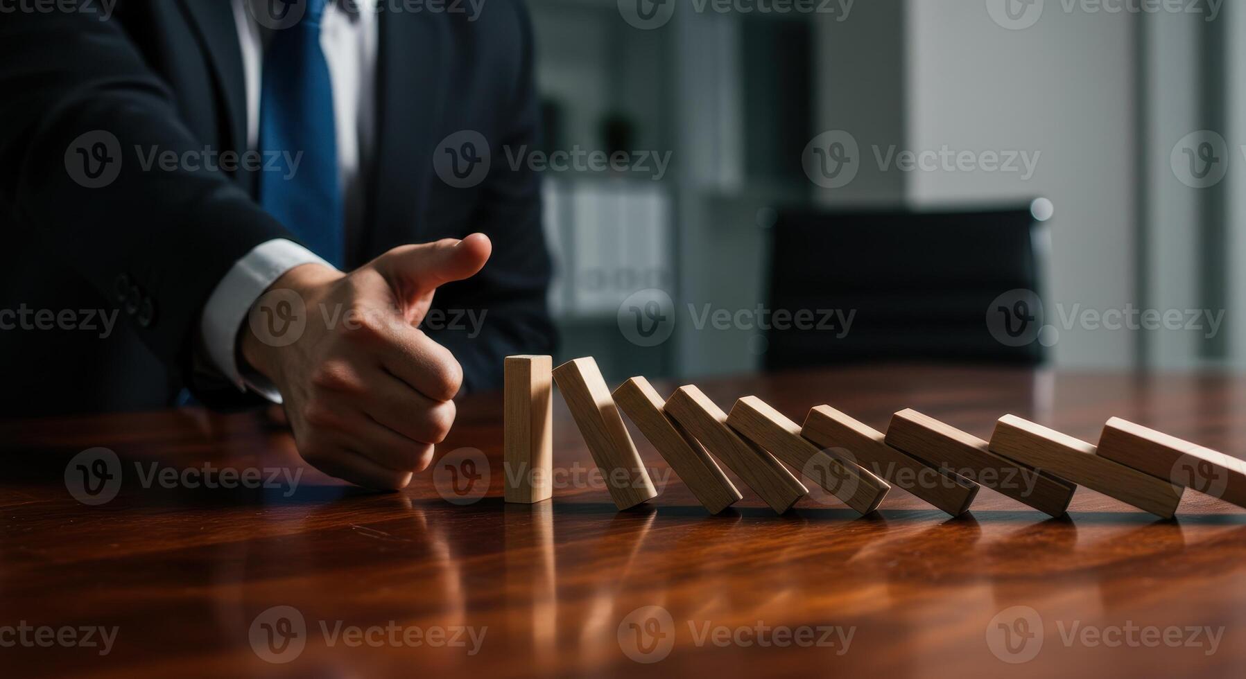 Businessman stopping wooden dominoes from falling on a desk, symbolizing crisis management, risk prevention, and business continuity planning. photo