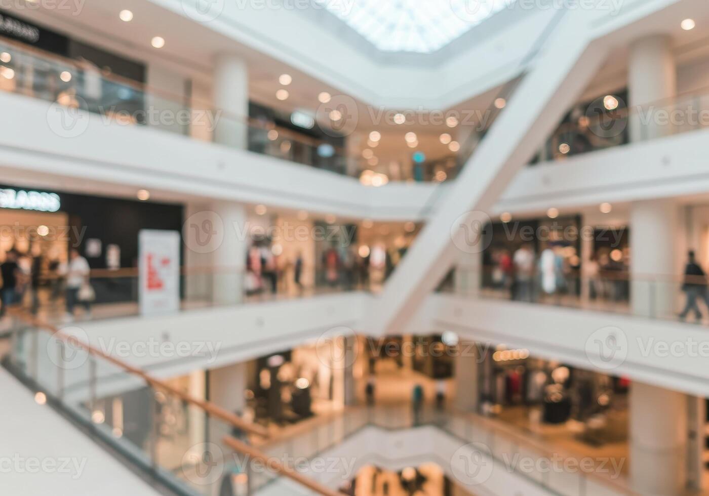 Blurred view of a multi level shopping mall with retail stores and escalators. Abstract image of a modern shopping center interior with shoppers and bright lighting. photo